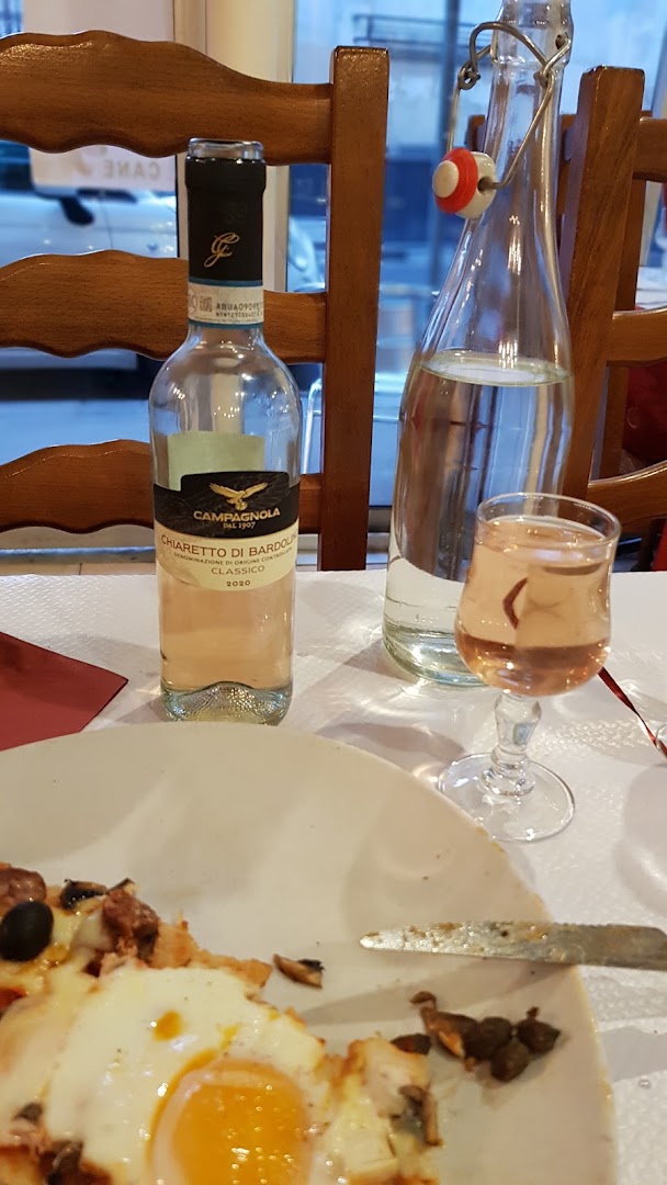 Une bouteille de vin, un verre et une pizza en bord de cadre